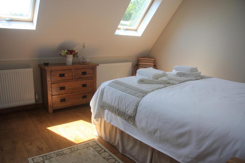 a bedroom with a bed with white sheets and two windows at Les Bouts de Rallé Chambre d&#39;Hotes in Sainte-Osmane