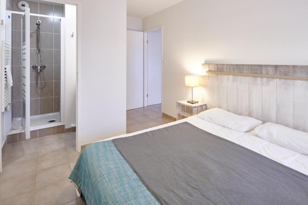 a bedroom with a large bed and a shower at Résidence Vacances Bleues Les Jardins d'Arvor in Bénodet