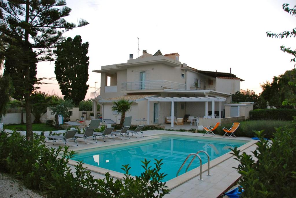 a villa with a swimming pool in front of a house at B&B Dunedorate in Punta Secca