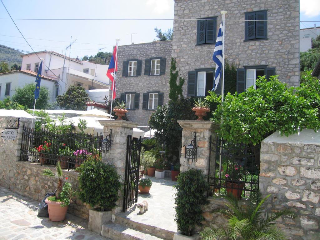 a house with two flags and a fence with plants at Mistral Hotel in Hydra