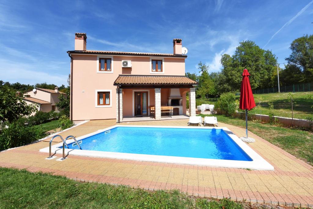 a villa with a swimming pool in front of a house at Villa Kmacici 377 in Sveti Lovreč Pazenatički