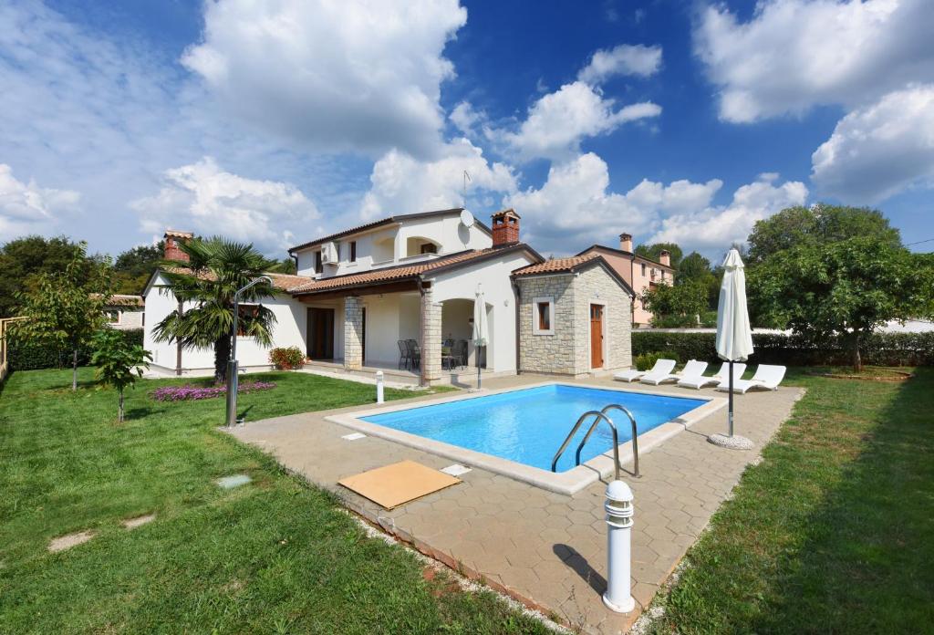 a villa with a swimming pool in front of a house at Villa Kmacici 376 in Sveti Lovreč Pazenatički