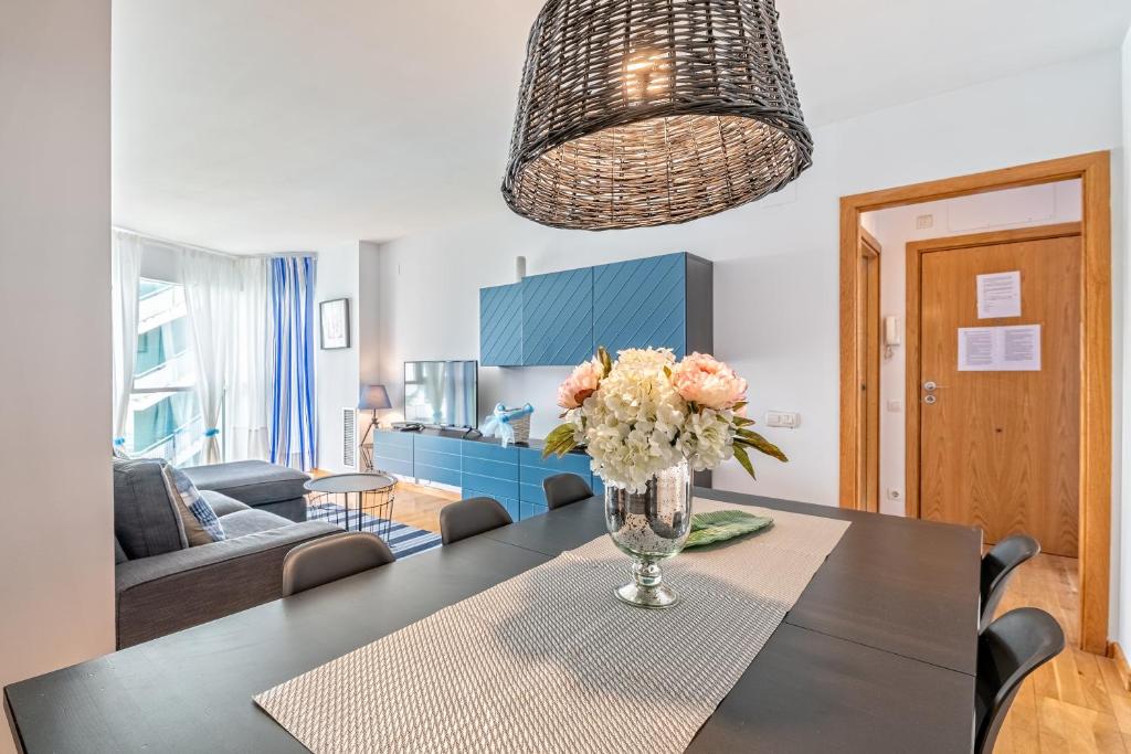 a dining room with a table with a vase of flowers at Apartamento lujo& piscina junto Barcelona Centro in Ripollet