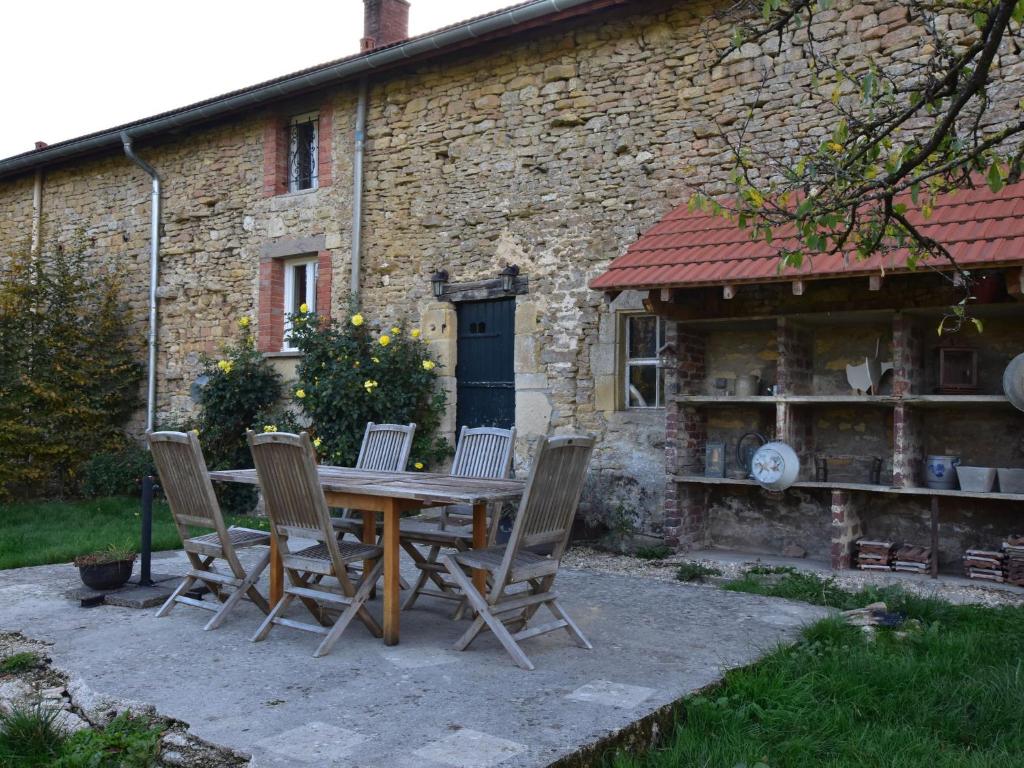 a wooden table and chairs in front of a building at Spacious holiday home near the forest in Barricourt