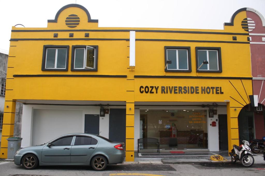 a car parked in front of a yellow building at Cozy Riverside Hotel in Melaka