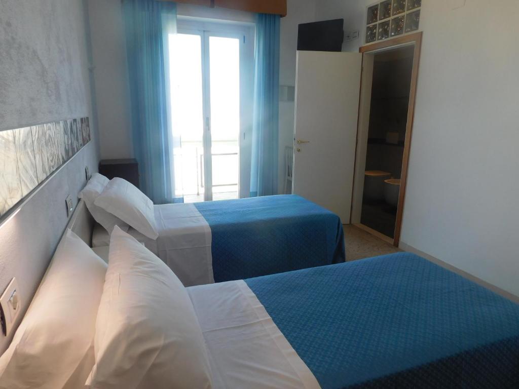 una camera d'albergo con due letti e una finestra di Hotel Dolores a Rimini