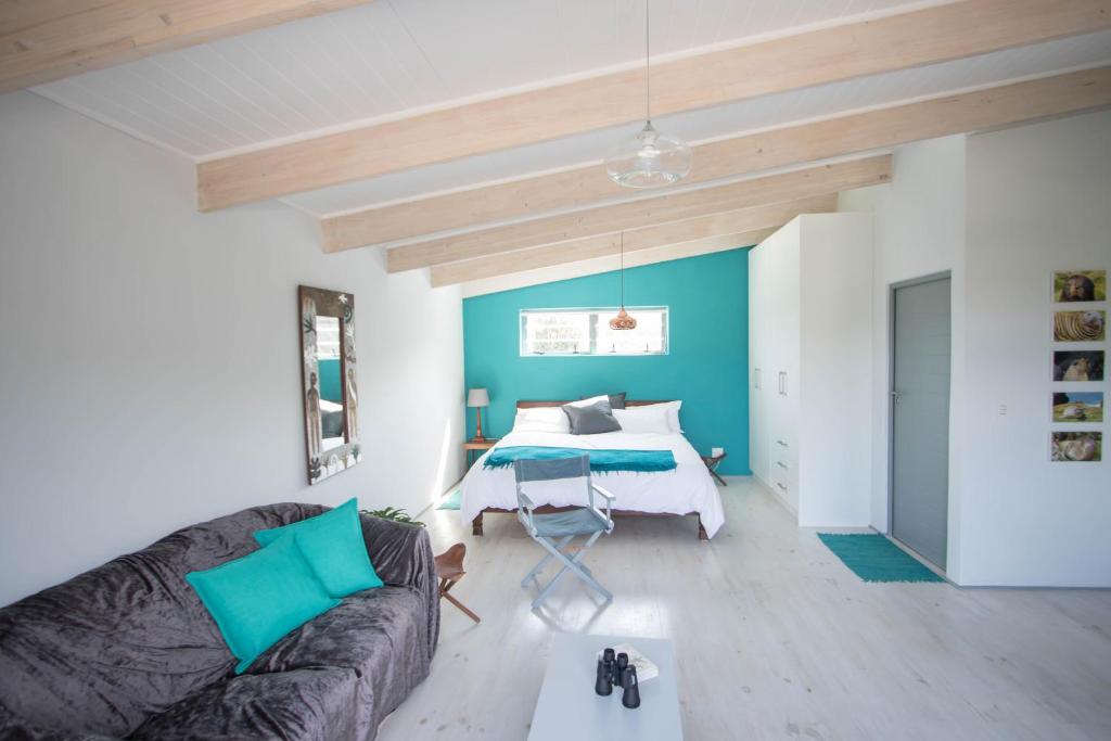 uma sala de estar com um sofá e uma cama em Selkie - Two Restful Studio Apartments near Noordhoek Beach & Restaurants em Noordhoek