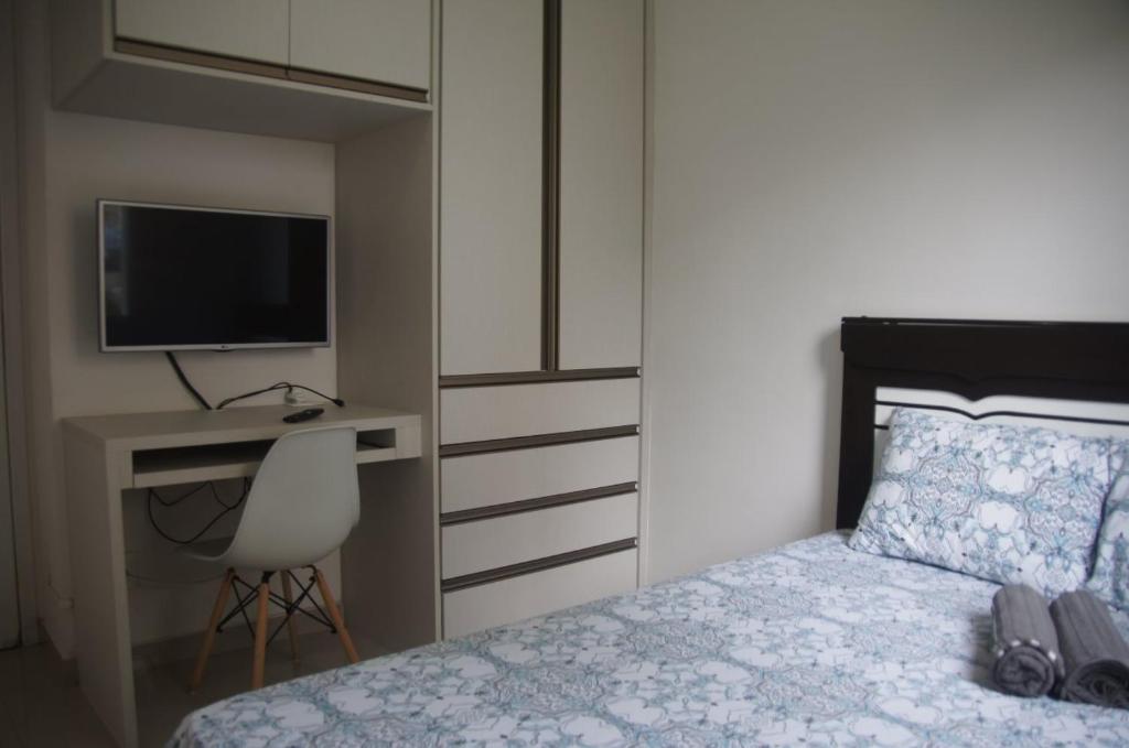 a bedroom with a bed and a desk and a television at Apartamento Completo em Cotia - SP in Cotia
