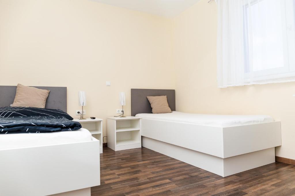 Duas camas num quarto com paredes brancas e pisos em madeira em Gästehaus Krause em Trumau