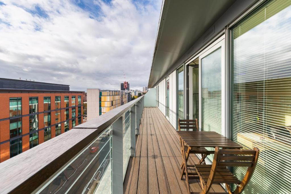 a balcony with a wooden table and chairs on a building at City Centre Penthouse in Birmingham