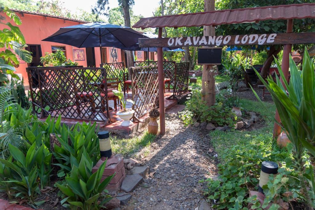 a garden with an umbrella and an entrance to a house at Okavango Lodge in Livingstone