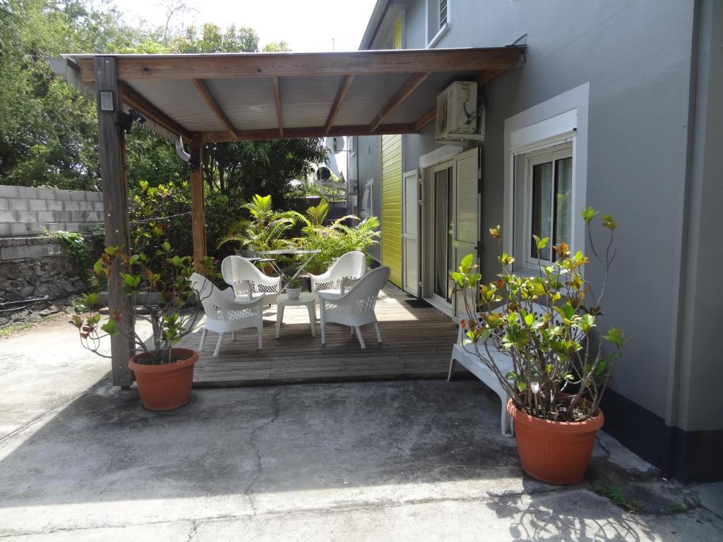 une terrasse couverte en bois avec une table, des chaises et des plantes dans l'établissement Residence Virginie, à Saint-Leu