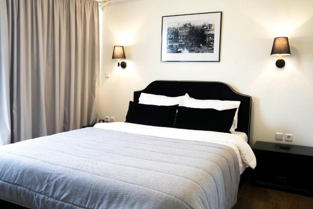 een slaapkamer met een groot wit bed met twee lampen bij Athens Edition Guesthouse in Athene