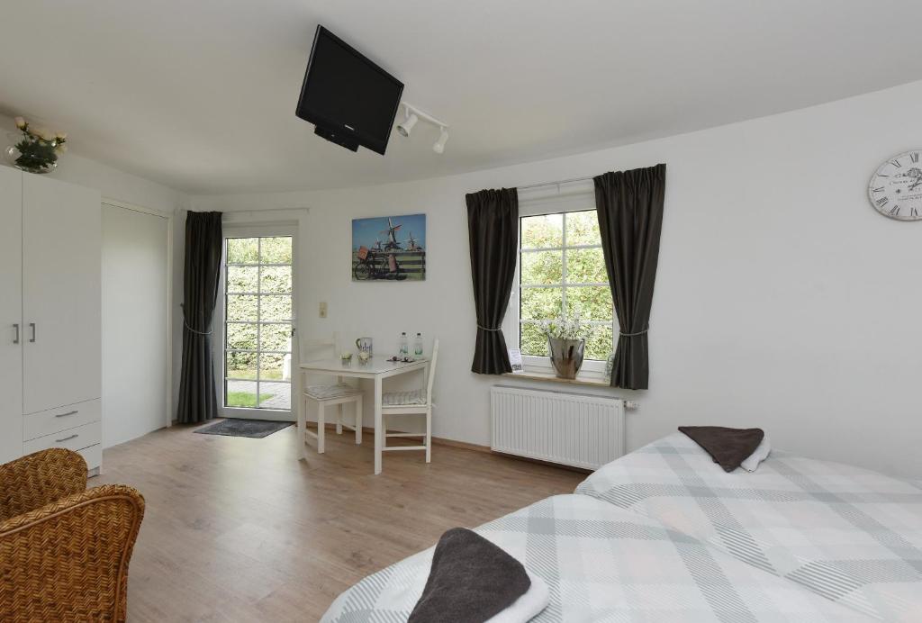 a bedroom with a bed and a desk and a television at De Witte Molen Kranenburg in Kranenburg