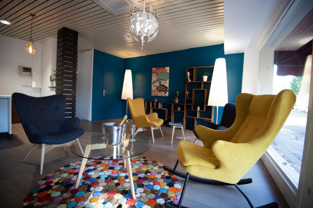 a living room with yellow and blue chairs and a table at Hotel Restaurant Saint-Benoit in Gueugnon