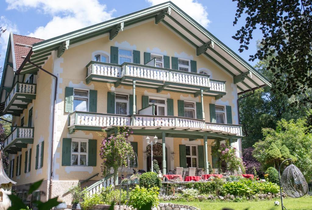 Una gran casa amarilla con persianas verdes en Villa Adolphine en Rottach-Egern