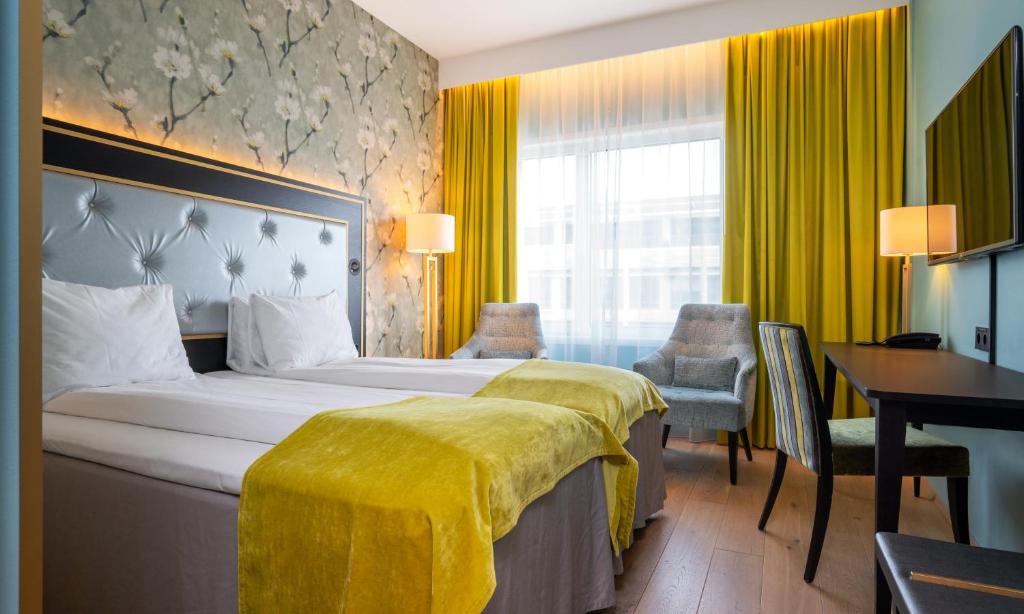 a hotel room with a bed with a yellow blanket on it at Thon Hotel Opera in Oslo