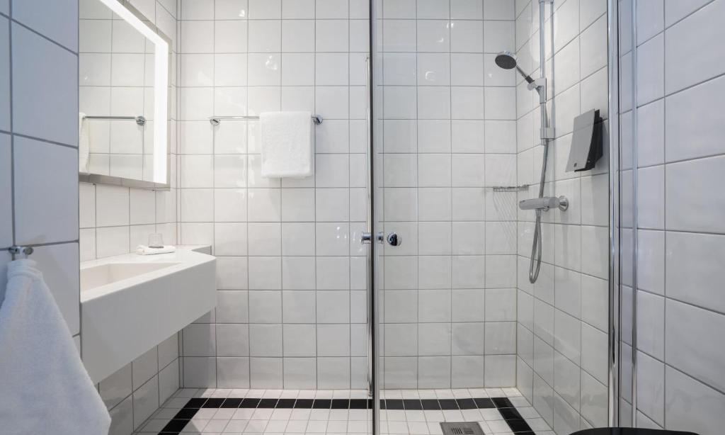 a white bathroom with a shower and a sink at Thon Hotel Opera in Oslo