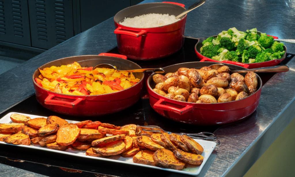 four pots of food on a counter with vegetables and potatoes at Thon Hotel Opera in Oslo