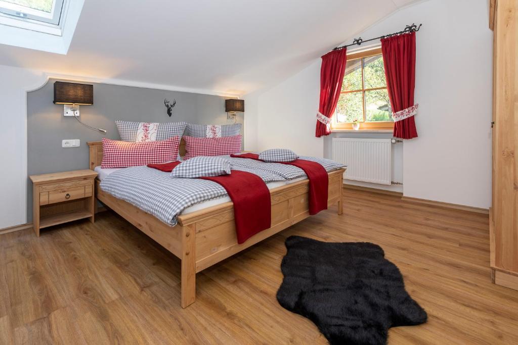 シェーナウ・アム・ケーニッヒスゼーにあるFerienwohnung Hirscheckのベッドルーム1室(赤いカーテンと窓付きのベッド1台付)