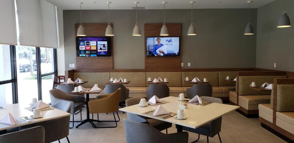 a dining room with tables and chairs and a tv at Wyndham Garden Ft Lauderdale Airport & Cruise Port in Dania Beach