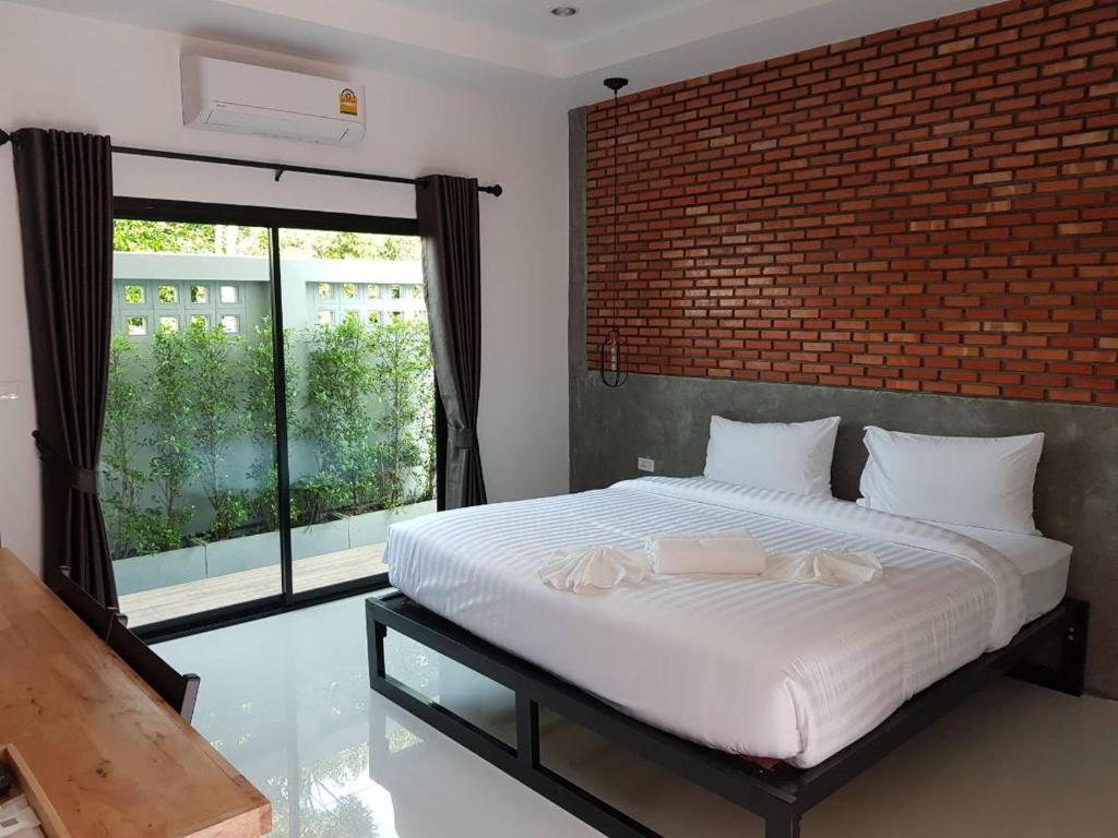 a bedroom with a large bed with a brick wall at Beloft Hotel in Nakhon Si Thammarat