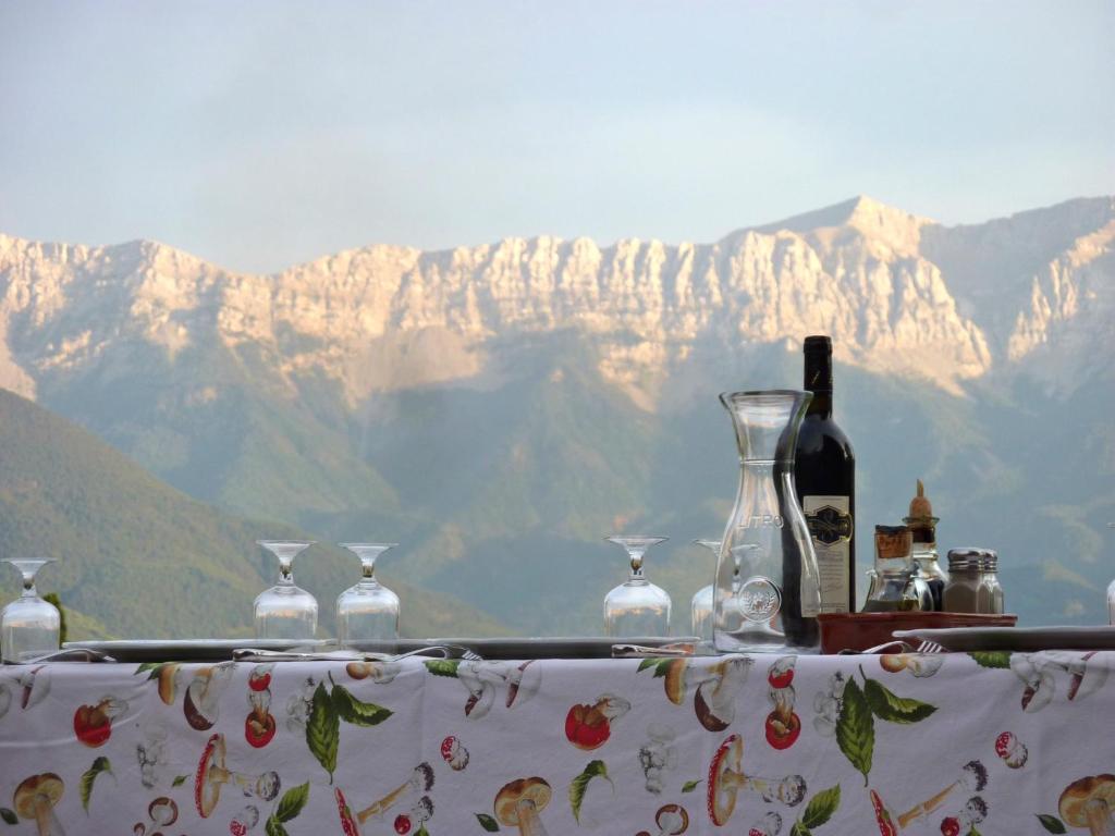a table with wine bottles and glasses on it with mountains at Casa rural calRei in Lles