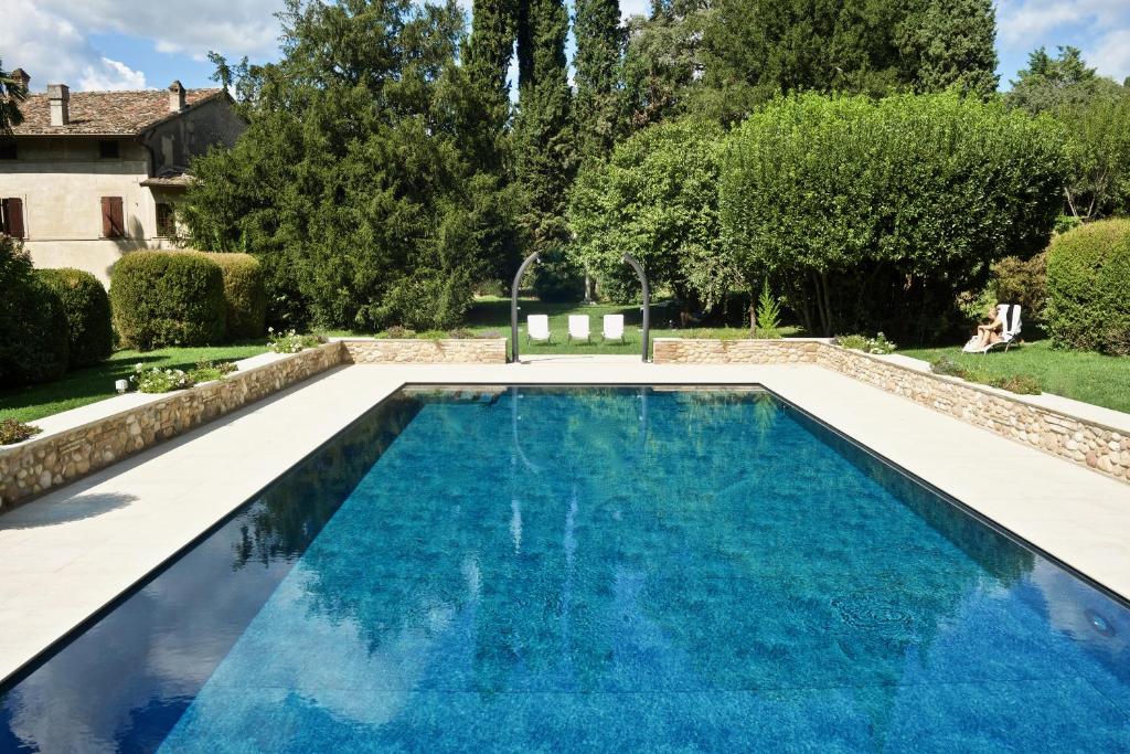 einen Pool in einem Garten mit blauem Wasser in der Unterkunft Solimago Dimora Storica in Solferino