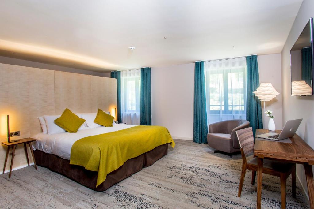 een hotelkamer met een bed, een bureau en een laptop bij Hôtel & Restaurant Sodade in Chaudes-Aigues