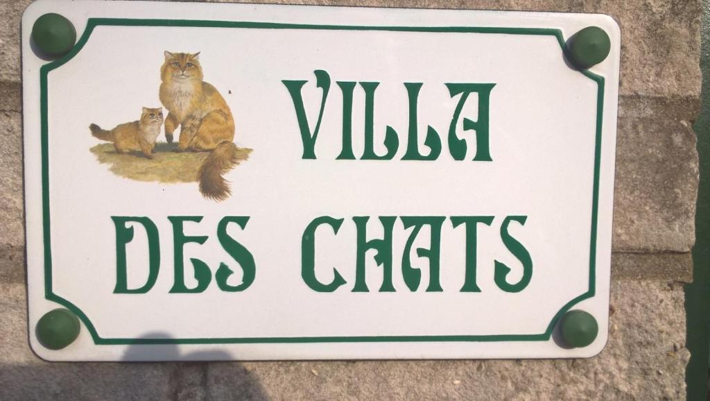 a sign with two cats sitting on a wall at la villa des chats in Andrésy
