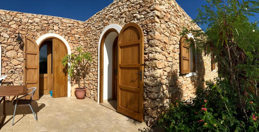 ランペドゥーザにあるDammuso Villaの木製のドアとパティオ付きの石造りの家