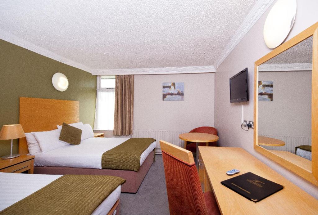 a hotel room with two beds and a desk at Treacys West County Conference and Leisure Centre in Ennis