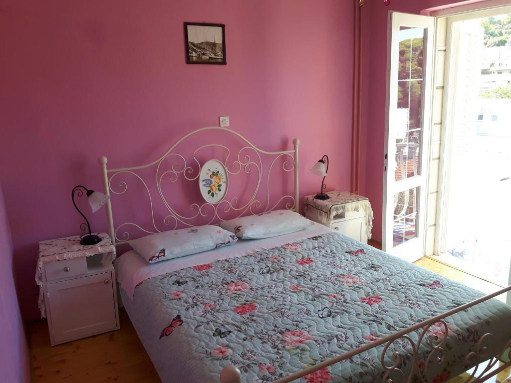 a bedroom with a bed with a pink wall at NOOR Apartment and Room in Hvar