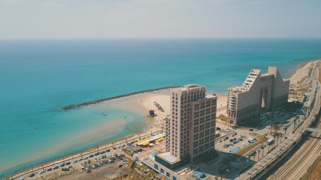 an aerial view of a beach with buildings and the ocean at מגדל אלמוג חיפה - דירות "בלו ביץ'" על הים in Haifa