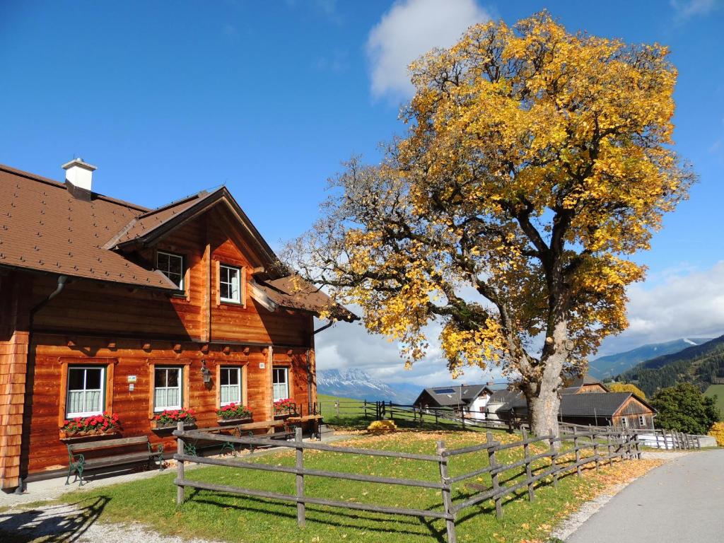 a wooden house with a tree and a fence at Ferienhaus Bichlhütte in Pruggern