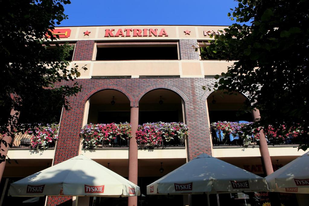 un edificio con flores en un balcón con sombrillas en Hotel Katrina, en Ostrzeszów