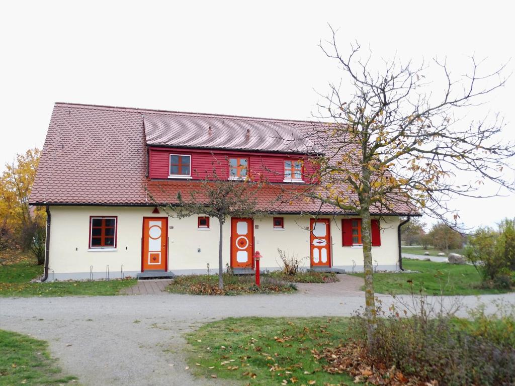 uma casa branca e vermelha com uma porta vermelha em Wowi Ferienwohnung B 53 em Dranske