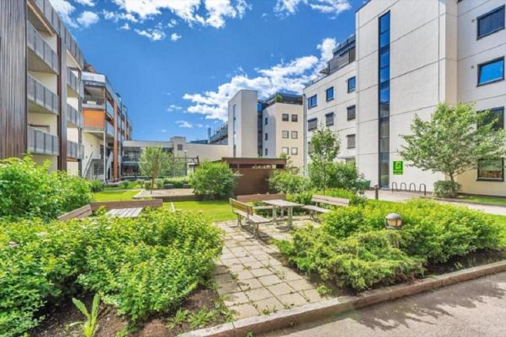 a park with benches and bushes in front of buildings at Sentral moderne leilighet in Lillestrøm