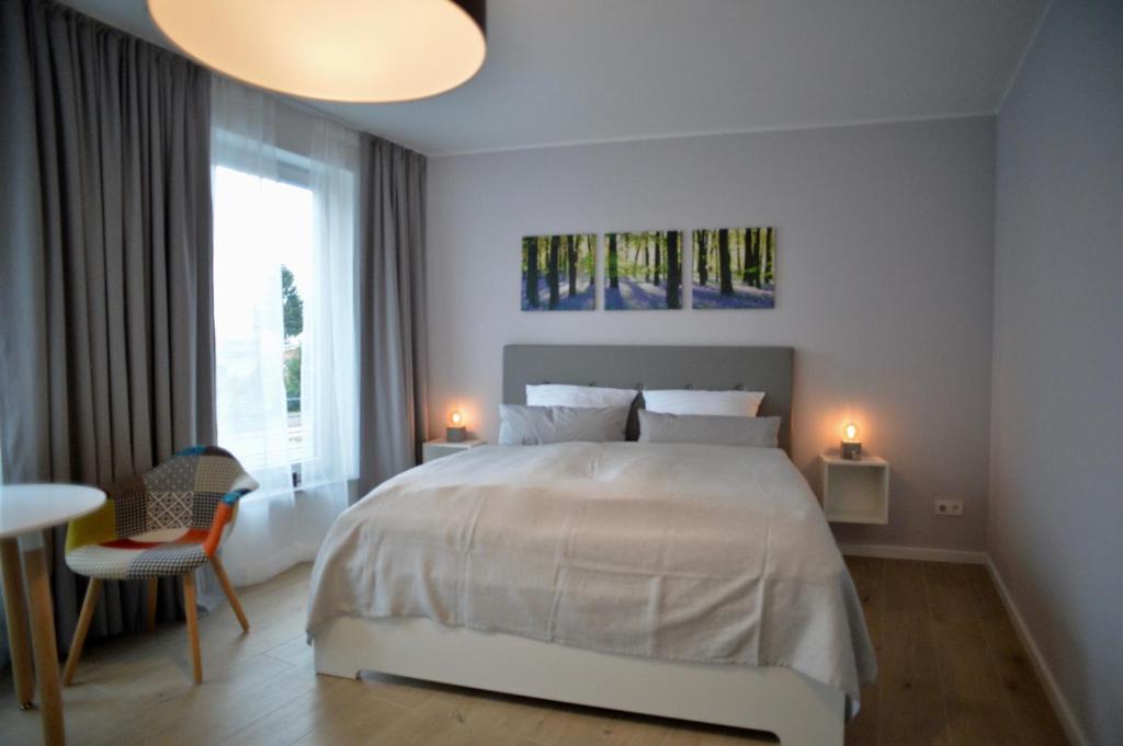 a white bedroom with a large bed and a window at Grey House Apartments Grossbeeren in Großbeeren
