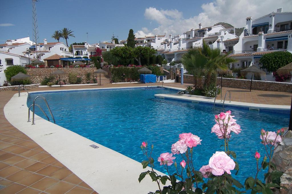 a swimming pool with some pink flowers and houses at Nerja Villas-Capistrano in Nerja