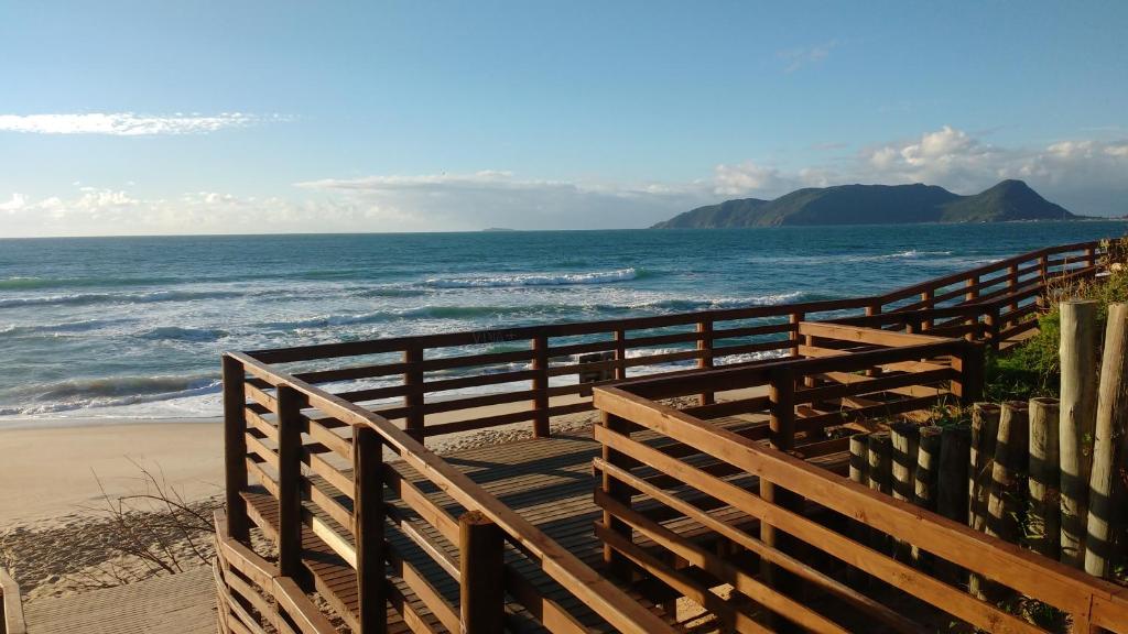 a wooden walkway to the beach with the ocean at Pousada Ilha do Campeche in Florianópolis