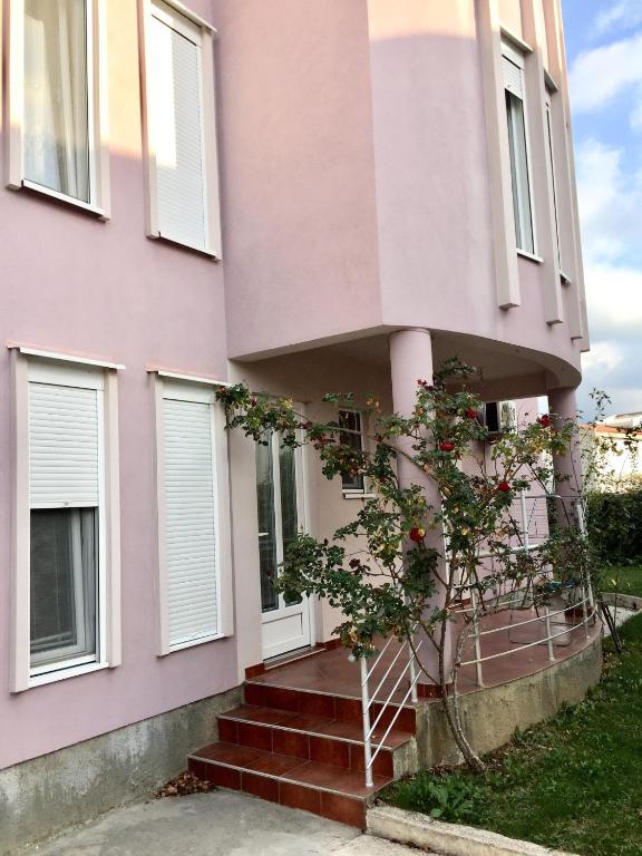 a pink house with a tree in front of it at Apartmani Milanovic Susanj in Bar