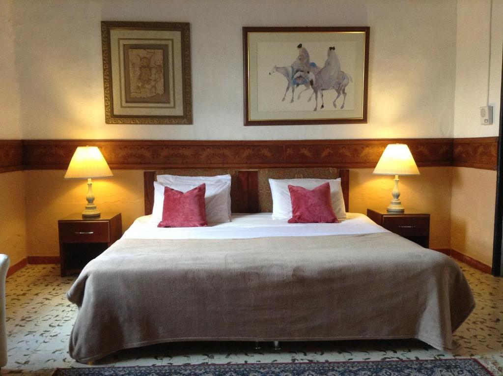 een hotelkamer met een groot bed met rode kussens bij HOTEL LA POSADA DEL ZAGUÁN in El Retiro