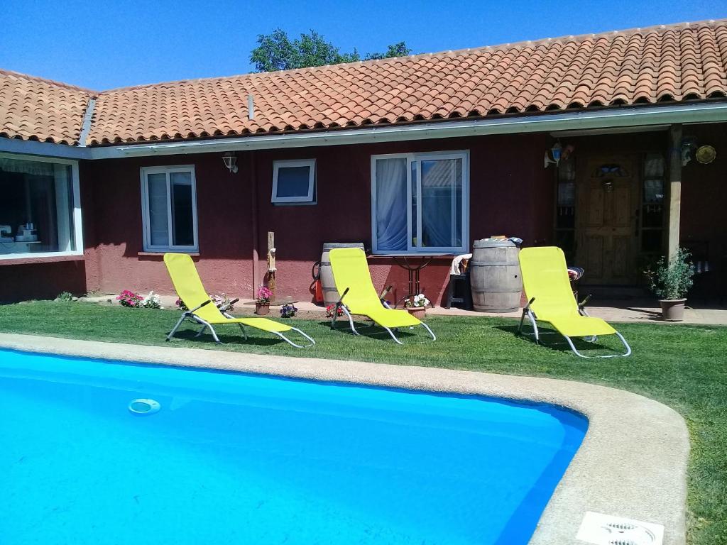a group of chairs and a swimming pool in front of a house at Alojamiento Los Nogales in Rancagua