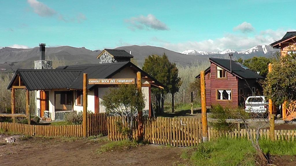 una casa de madera con una valla delante en Cabañas Boca del Chimehuín en Junín de los Andes