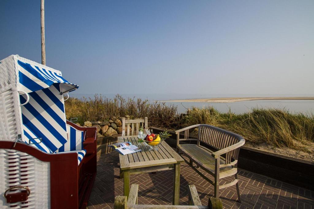 - une table et des chaises sur une terrasse avec vue sur l'océan dans l'établissement Ferienhaus *Traumblick*, à Wittdün