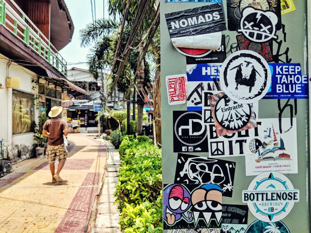 a man walking down a street with stickers on a wall at Lucky Dorm in Phi Phi Islands