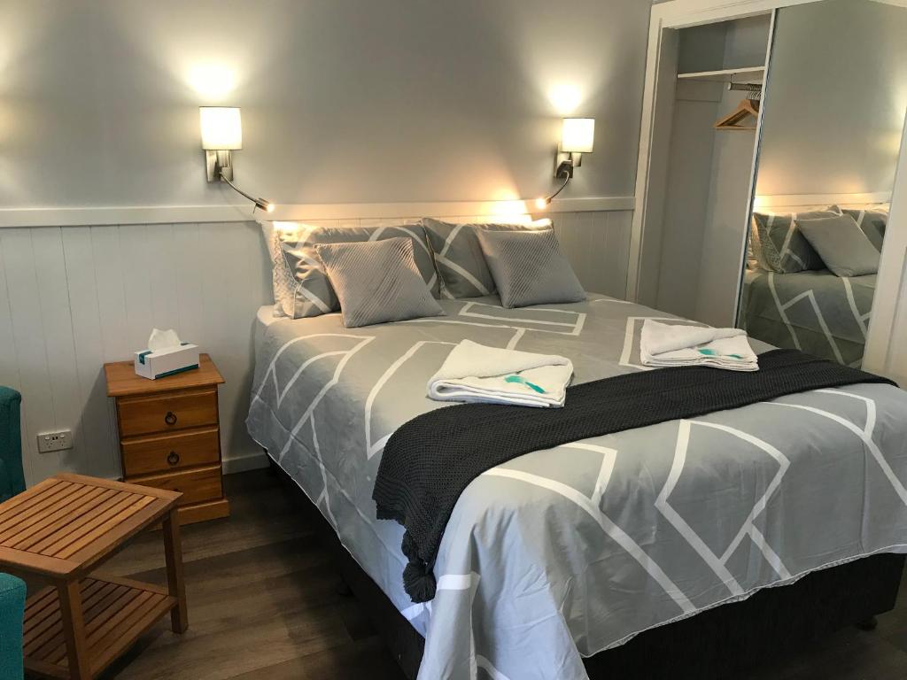 a bedroom with a large bed with towels on it at Ulladulla Motel in Ulladulla