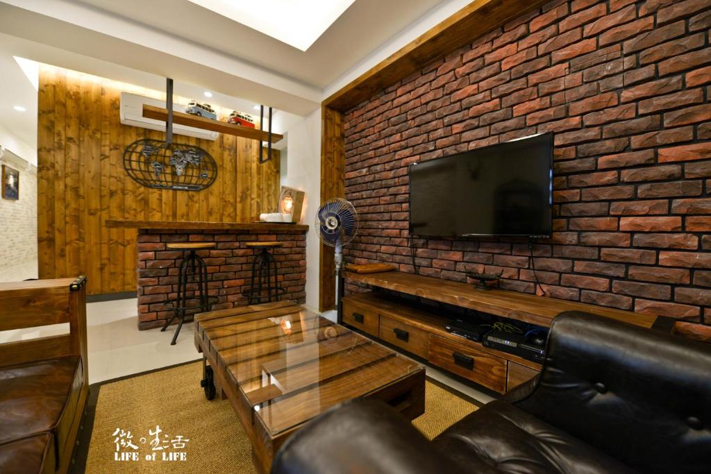 a living room with a brick wall and a tv at Siamo in Tainan
