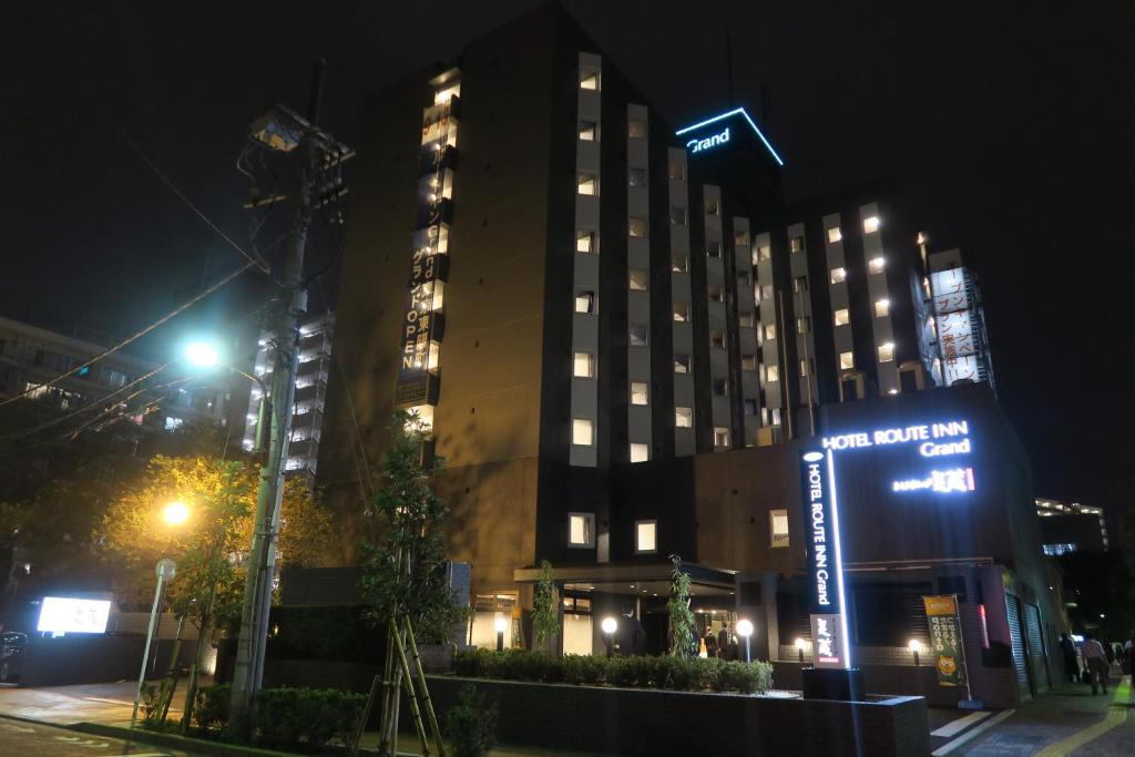 a tall building with a sign in front of it at night at Hotel Route-Inn Grand Tokyo Toyocho in Tokyo